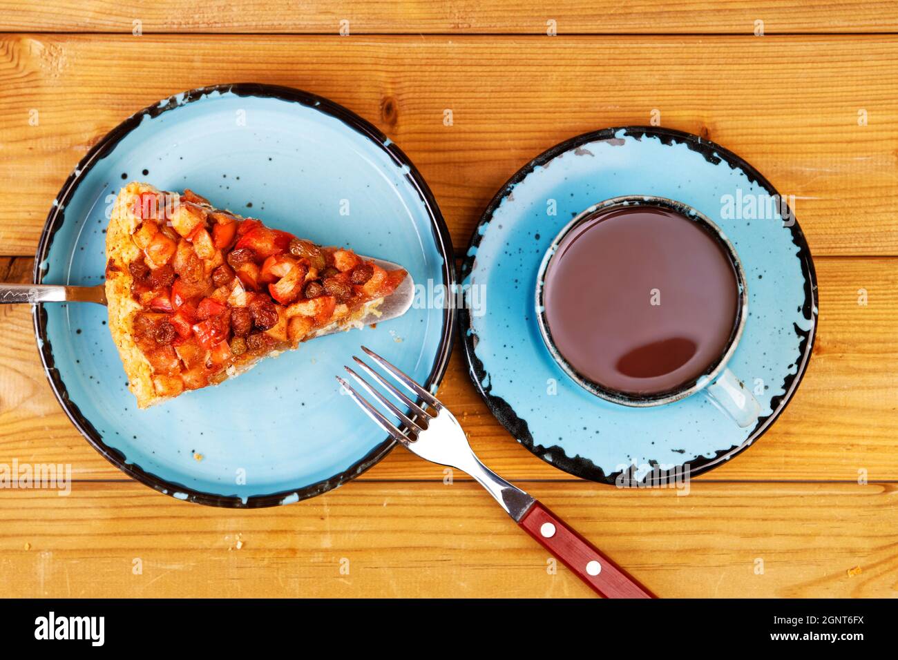 Tasse de thé et morceau de tarte maison avec pommes, raisins secs et cannelle sur table en bois. Vue de dessus. Banque D'Images Tasse de thé et morceau de tarte maison avec pommes, raisins secs et cannelle sur table en bois. Vue de dessus. Banque D'Images