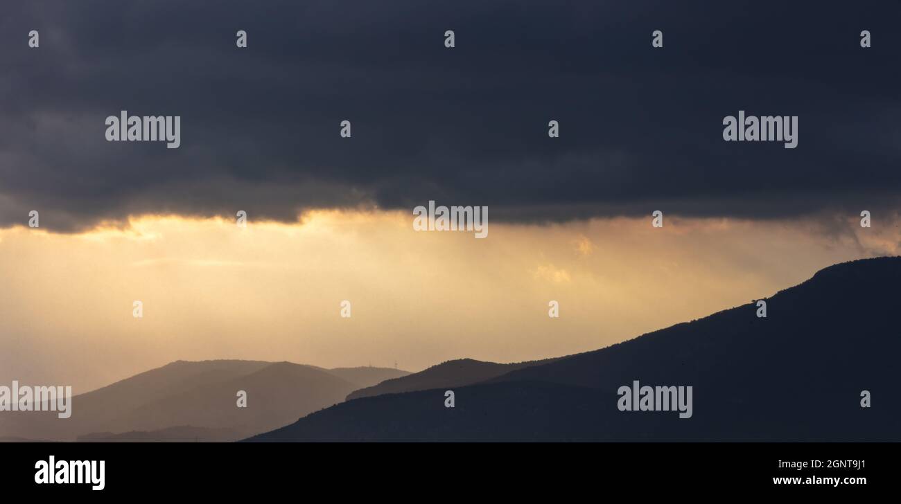 Nuages gris foncé sur un ciel spectaculaire au coucher du soleil, sur l'arrière-plan, l'espace. Paysage de nuages lourds sur les montagnes. Mauvais temps, pluie et orage. natura pluvieuse Banque D'Images