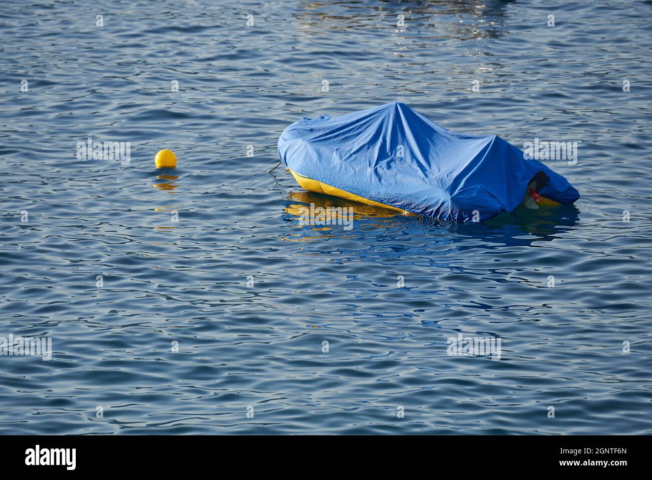 Bateau en caoutchouc recouvert d'une couverture dans l'eau de mer Banque D'Images
