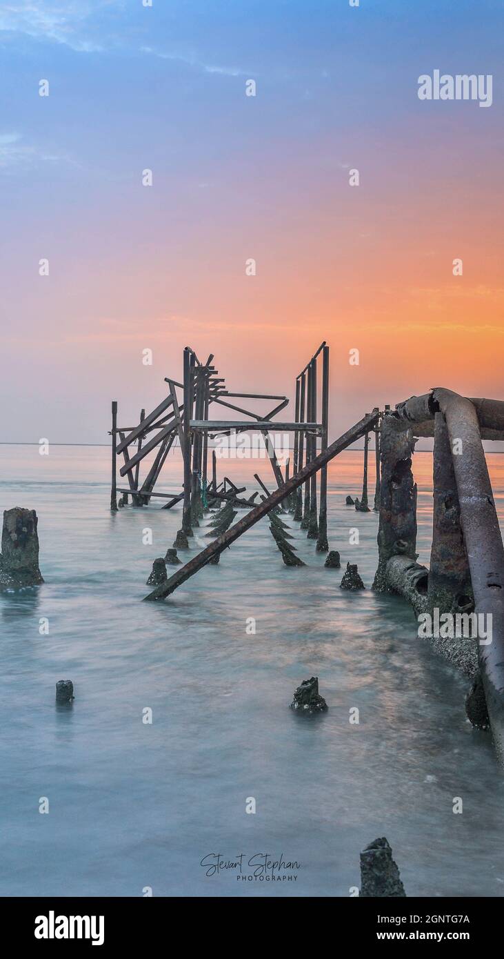 C'est un pont ou quelque chose étant en mer et son abandonné avec belle couleur de lever du soleil . Banque D'Images