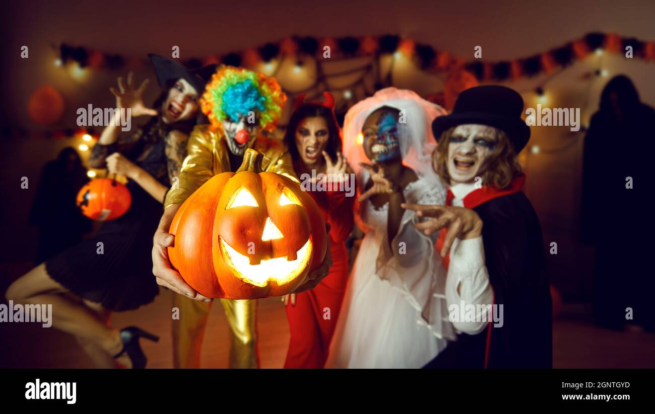 Groupe d'amis adultes avec une Jack-o-lanterne s'amusant à une fête de costume à la maison Banque D'Images