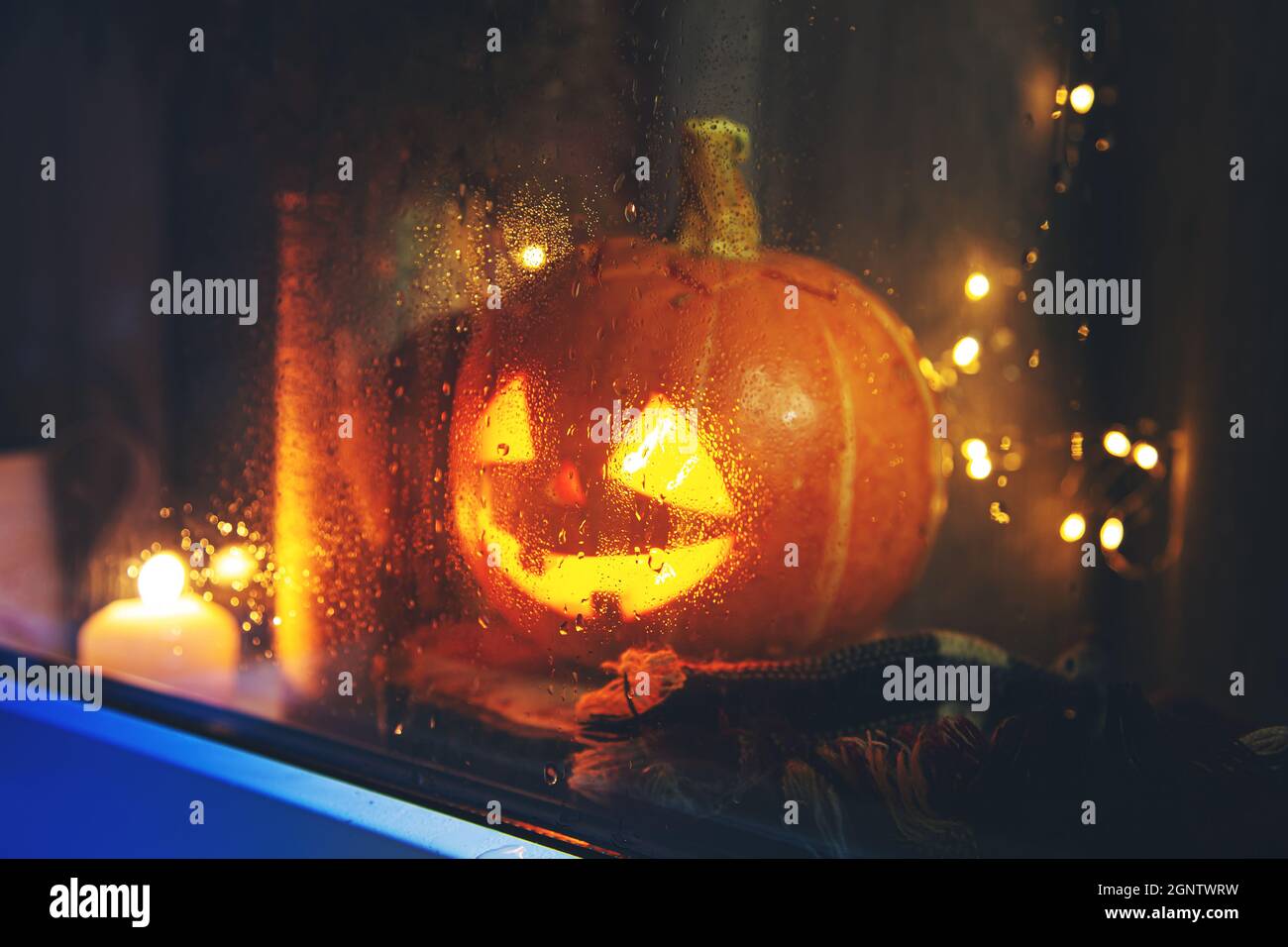La citrouille sculptée donne sur la fenêtre. Jack Lantern, Halloween concept. Pluvieux, automne. Mise au point sur le verre. Banque D'Images