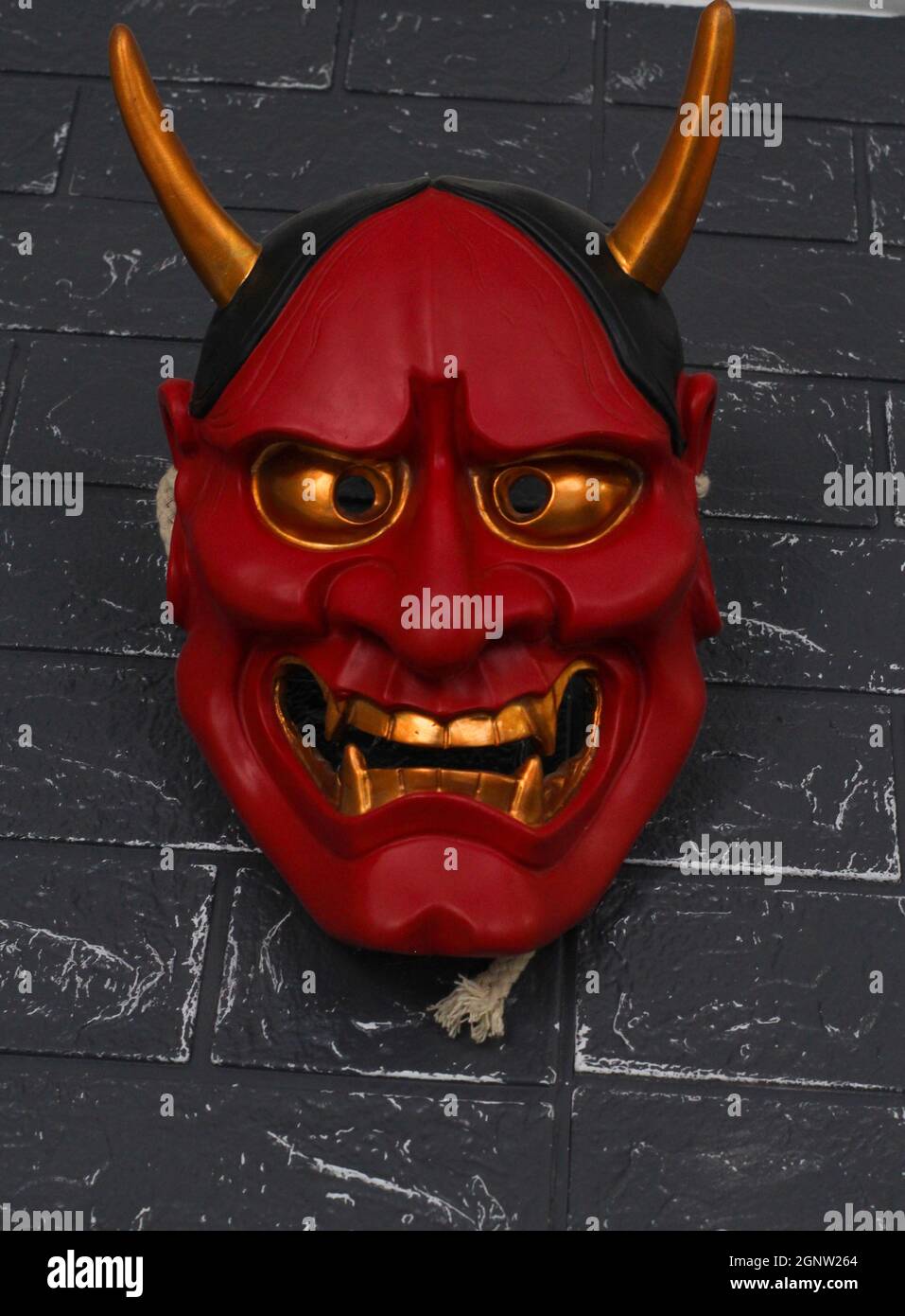 Plan vertical d'un masque de diable sur un mur de brique noire - Halloween concept Banque D'Images