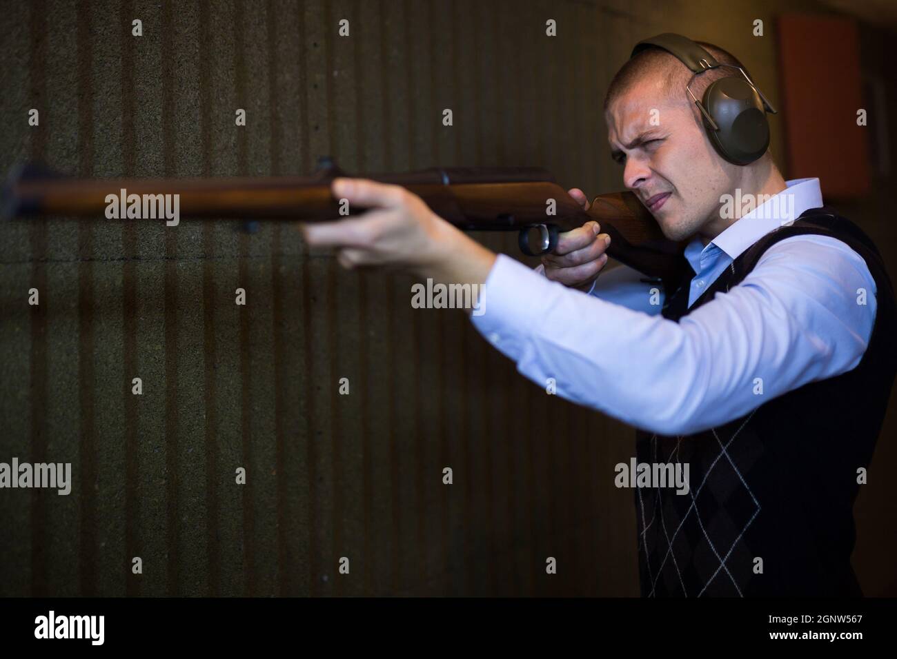 Homme concentré pratiquant le tir au fusil de chasse au champ de tir Banque D'Images