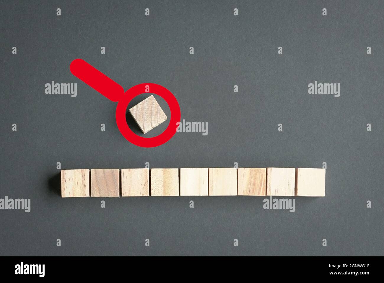 Cubes de bois sur une rangée et un seul cube à l'extérieur de la rangée avec icône de loupe en haut. Concept de leadership ou de sortie. Banque D'Images