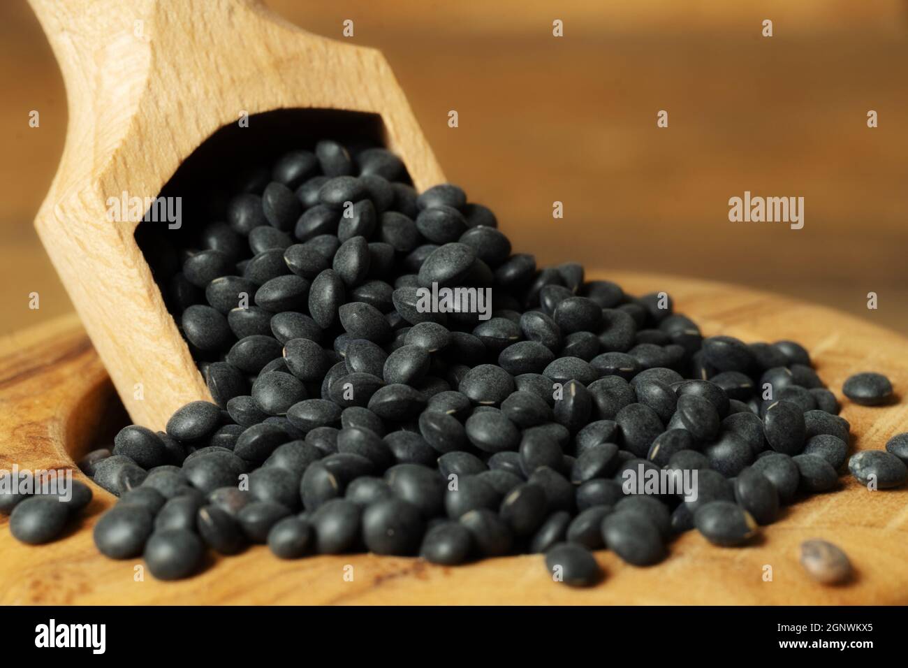 Gros plan de béluga lentilles n un bol avec une pelle. Béluga lentilles dans un bol en bois sur fond en bois. Banque D'Images