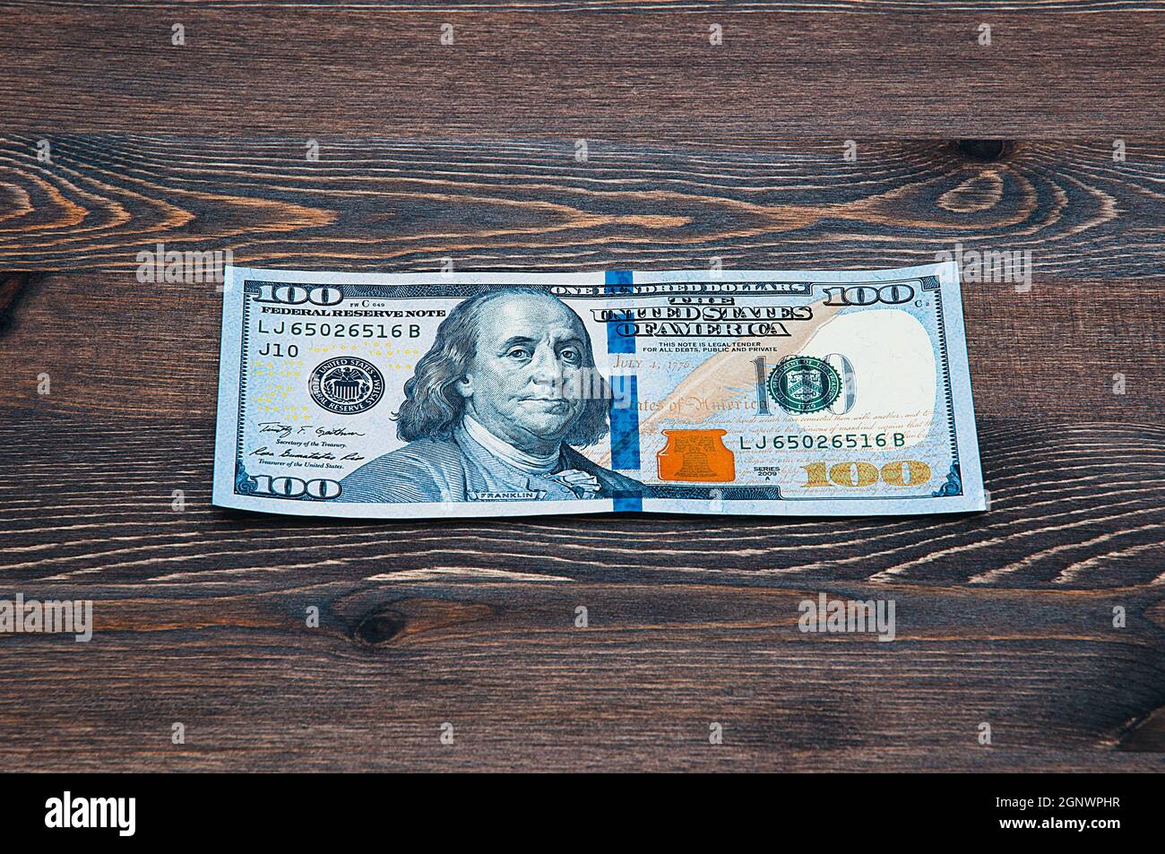 une facture de cent dollars en espèces sur une table en bois sombre. Maquette, mise en page. Banque D'Images