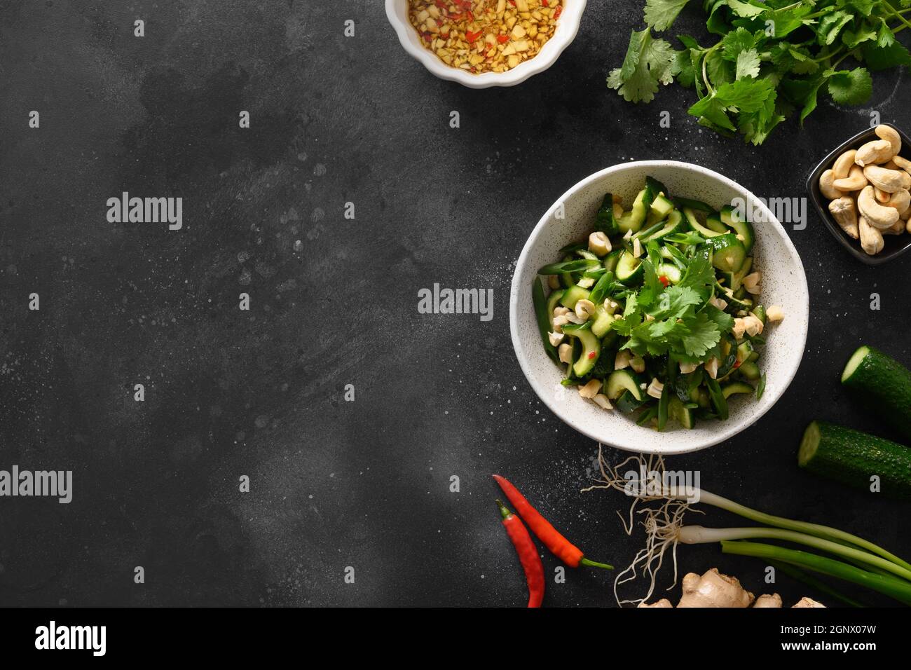 Salade asiatique épicée de concombres brisés avec coriandre, gingembre, piment, vinaigre noir sur fond noir avec espace de copie. Concombres épicés. Vue de Banque D'Images