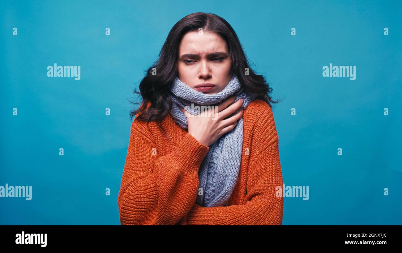 femme malade dans une écharpe chaude touchant le cou tout en souffrant de  douleur dans la gorge isolée sur bleu Photo Stock - Alamy