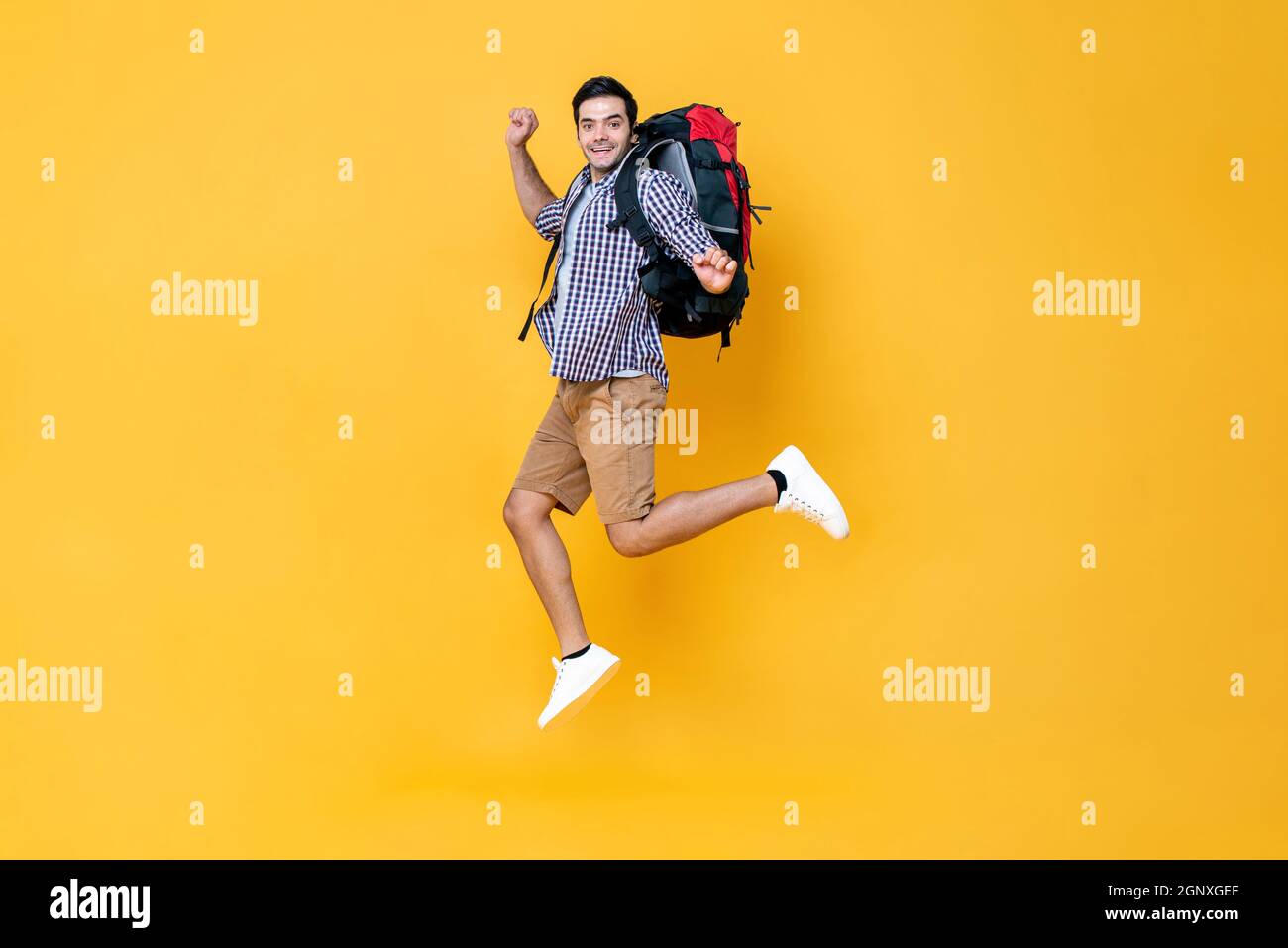 Excitée jeune caucasien touriste routard saut en plein air isolé sur fond jaune studio Banque D'Images