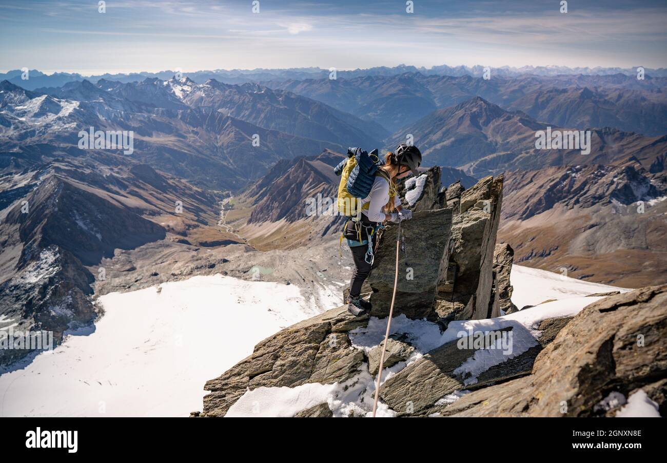 Femme grimpant la formation naturelle de roche et essayant d'atteindre le sommet de montagne.Au coucher ou au lever du soleil.Concept de l'escalade alpine.Crête de Studlgrat Banque D'Images