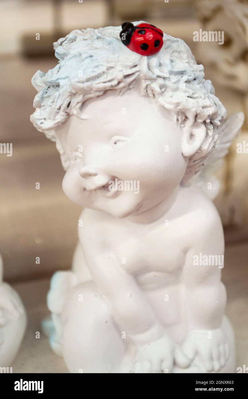 Belle petite statue d'ange. Détail et portrait de la coupole assise avec coccinelle. Image verticale Banque D'Images