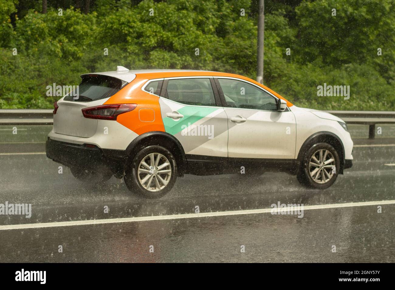 La voiture roule sur une route humide. Route glissante après la pluie. Éclaboussures sous les roues de transport. Pluie sur l'autoroute. L'été en baisse dans les s. Banque D'Images