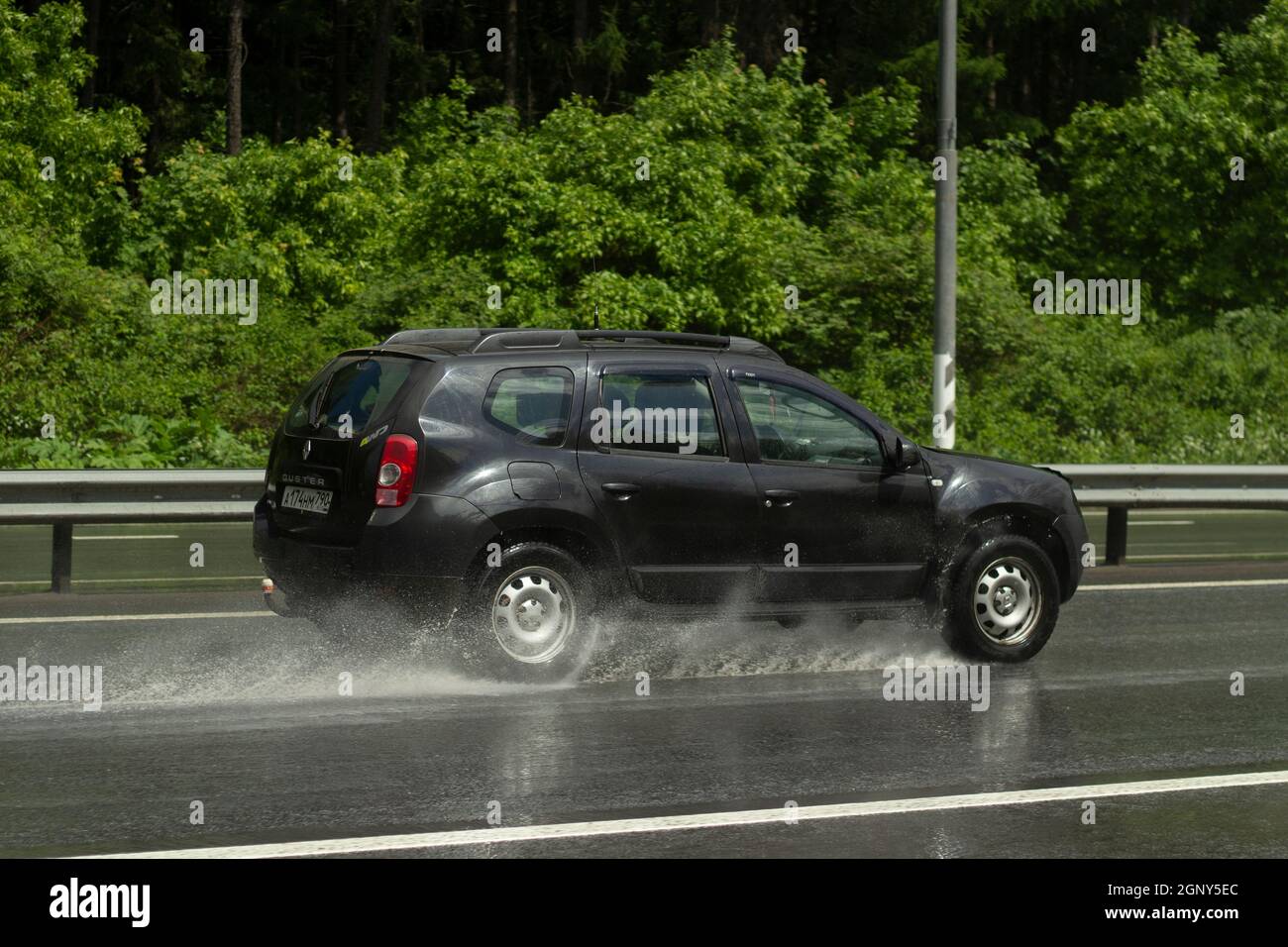 La voiture roule sur une route humide. Route glissante après la pluie. Éclaboussures sous les roues de transport. Pluie sur l'autoroute. L'été en baisse dans les s. Banque D'Images