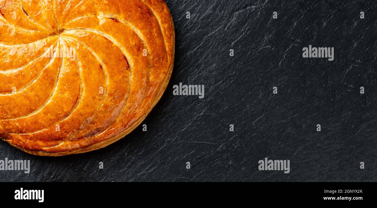 Epiphany cake ou galette des rois en français sur fond d'ardoise noire, recadrage panoramique avec espace de copie Banque D'Images