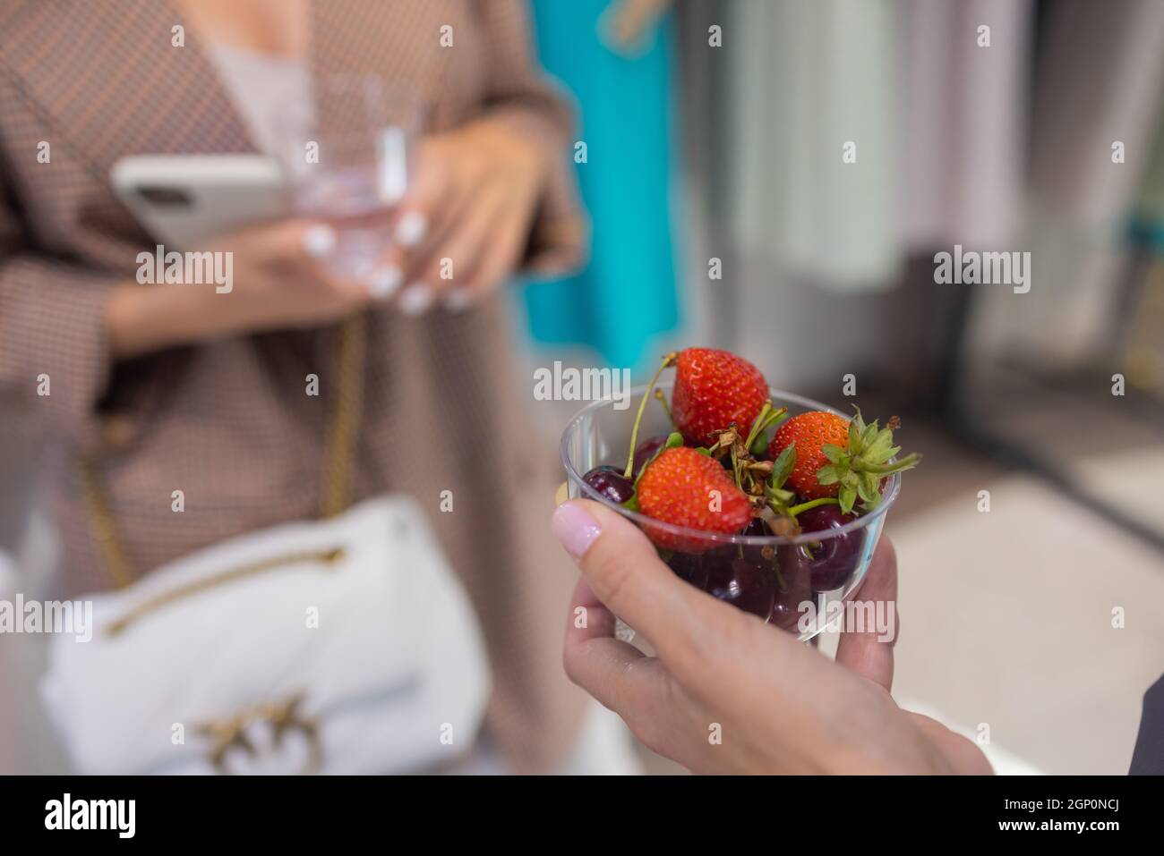 La fillette de cuisine tient un pot de dessert aux fruits et de fraises entre ses mains Banque D'Images