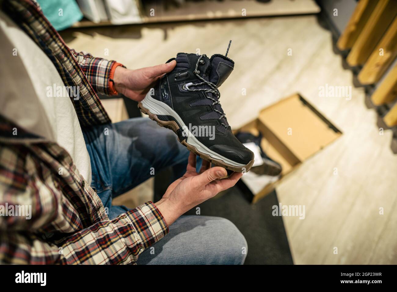 L'homme caucasien choisit et mesure des bottes de randonnée dans un magasin de sport et de voyage. Homme regardant des chaussures de randonnée dans une boutique en plein air. Chaussures de randonnée pour hommes Banque D'Images