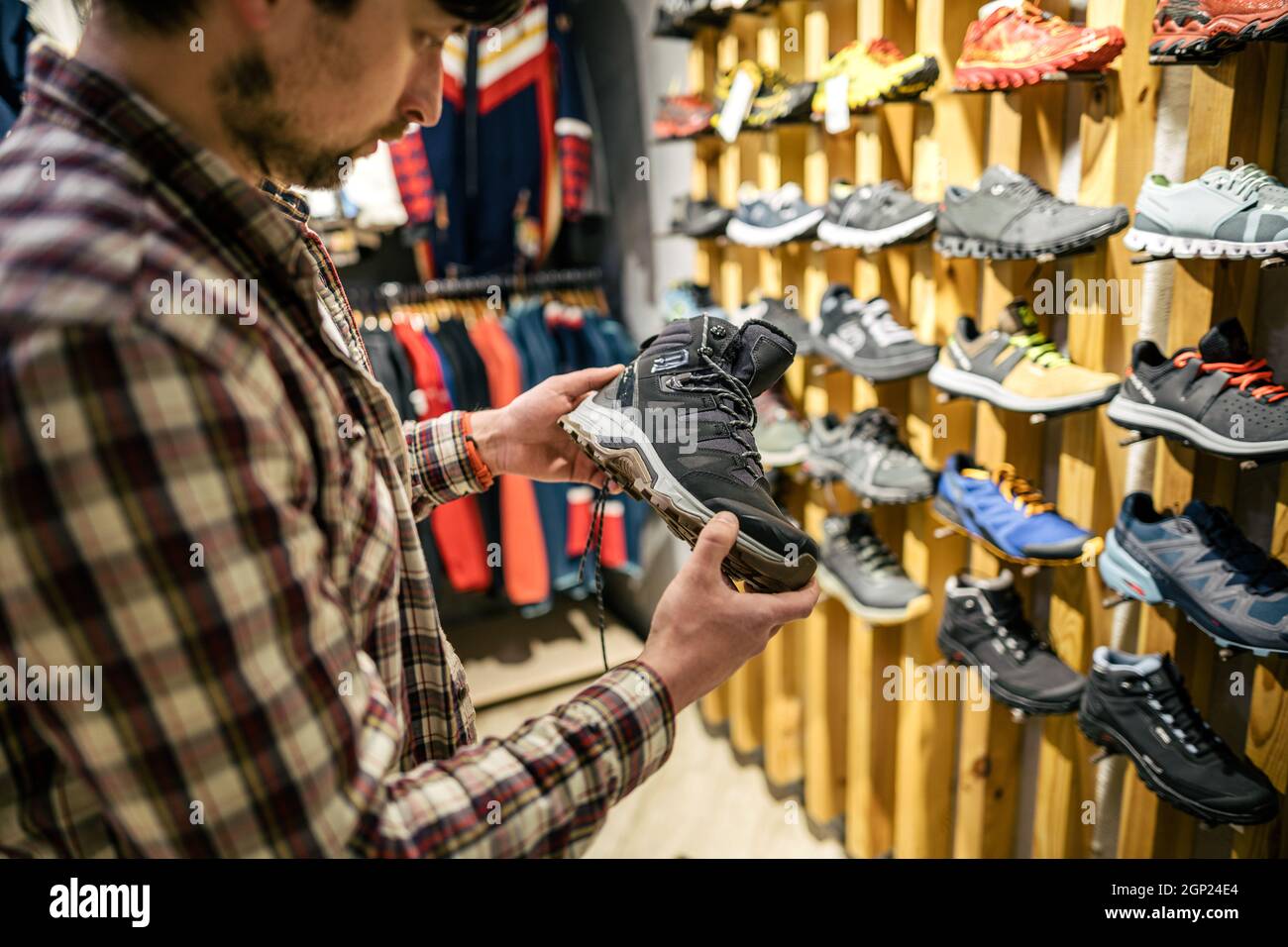 L'homme caucasien choisit et mesure des bottes de randonnée dans un magasin de sport et de voyage. Homme regardant des chaussures de randonnée dans une boutique en plein air. Chaussures de randonnée pour hommes Banque D'Images