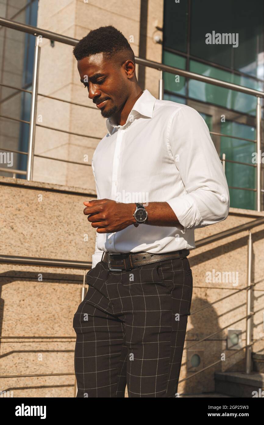 Jeune homme africain noir élégant en chemise blanche et pantalon classique  marchant à l'extérieur. Portrait de style de vie Photo Stock - Alamy