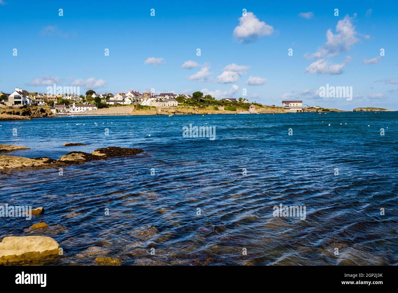 Vue sur la mer jusqu'au bord de mer du village avec station de canot de sauvetage et île. Moelfre, Île d'Anglesey, pays de Galles du Nord, Royaume-Uni, Grande-Bretagne, Europe Banque D'Images