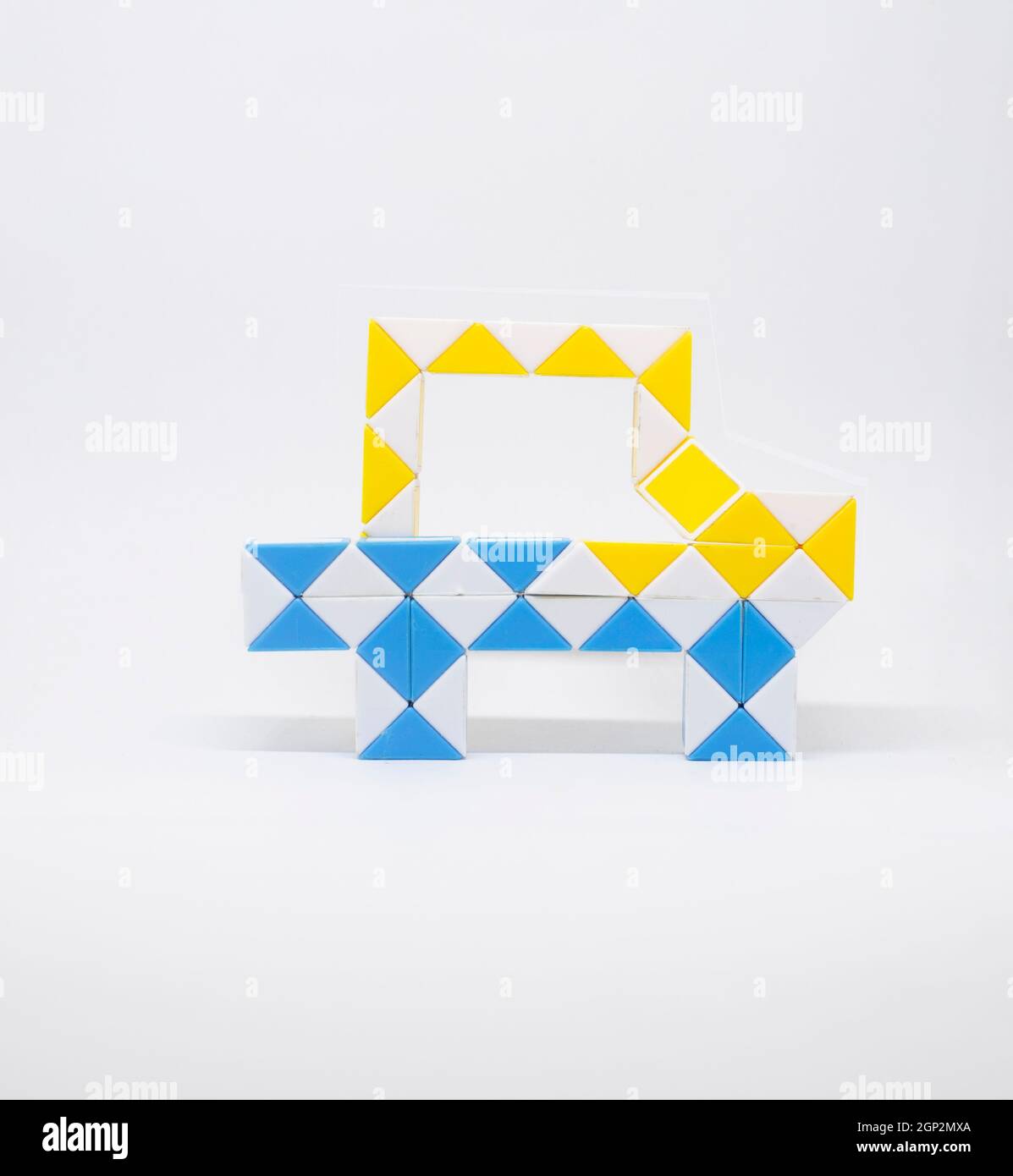 Voiture de jouet faite de triangles bleus, jaunes et blancs sur fond blanc. Banque D'Images