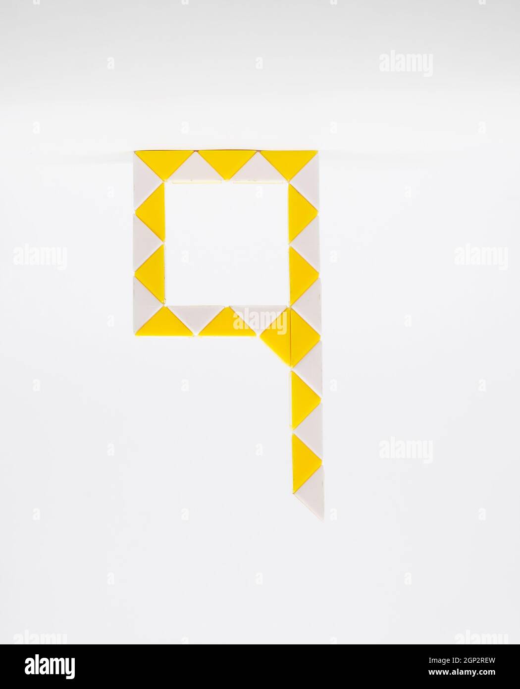 Lettre « q » composée de triangles jaunes et blancs sur fond blanc. Banque D'Images
