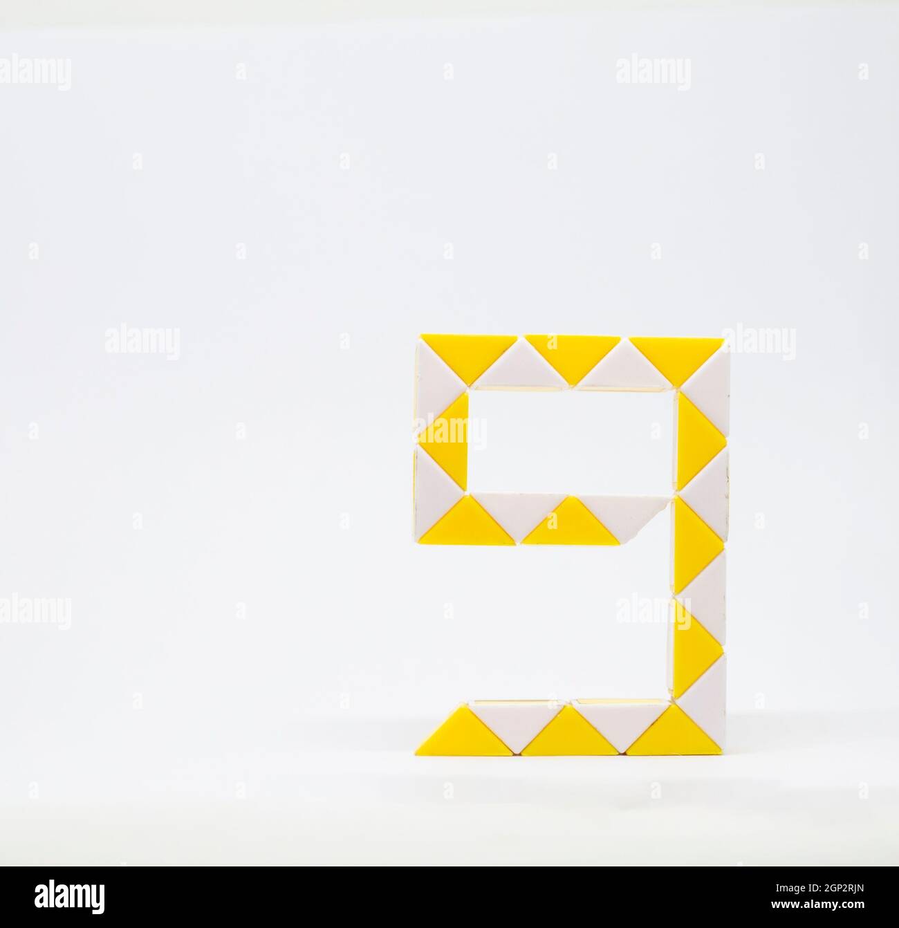 Lettre « g » composée de triangles jaunes et blancs sur fond blanc. Banque D'Images