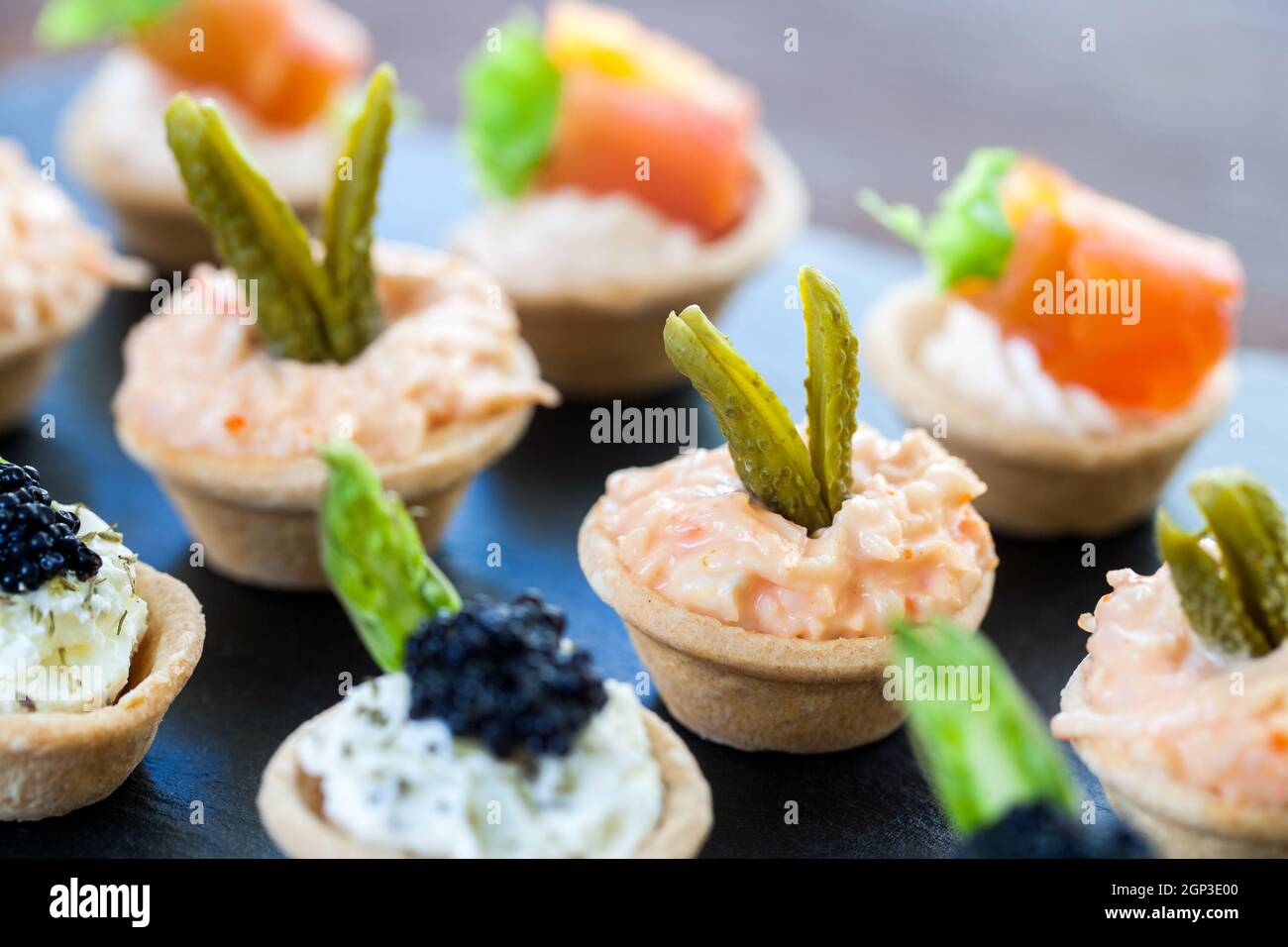 Macro gros plan de plusieurs mini tartelettes à pâtisserie avec variété de farce de fruits de mer. Banque D'Images