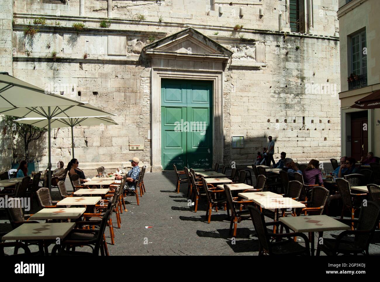 Nîmes - France - avril 24 2011 : Cathédrale avec terrasses de cafés dans la charmante place aux herbes les touristes se détendent avant le déjeuner Paysage aspect tourné W Banque D'Images