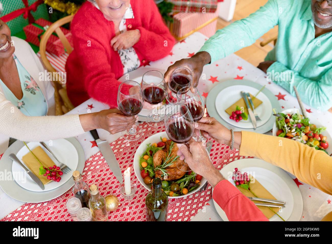Milieu de groupe diversifié d'amis aînés heureux célébrant noël avec la vigne ensemble à la maison Banque D'Images