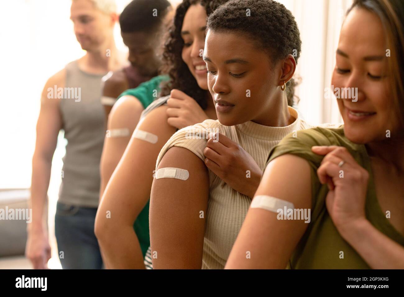 Groupe d'amis féminins et masculins divers montrant des emplâtres après la vaccination Banque D'Images