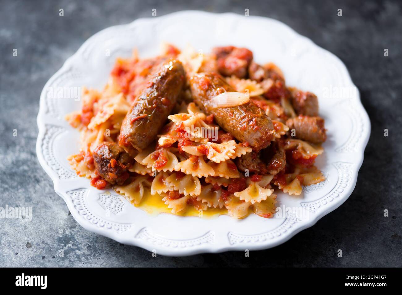 gros plan de l'assiette de pâtes italiennes à la saucisse farfalle dans la sauce tomate Banque D'Images