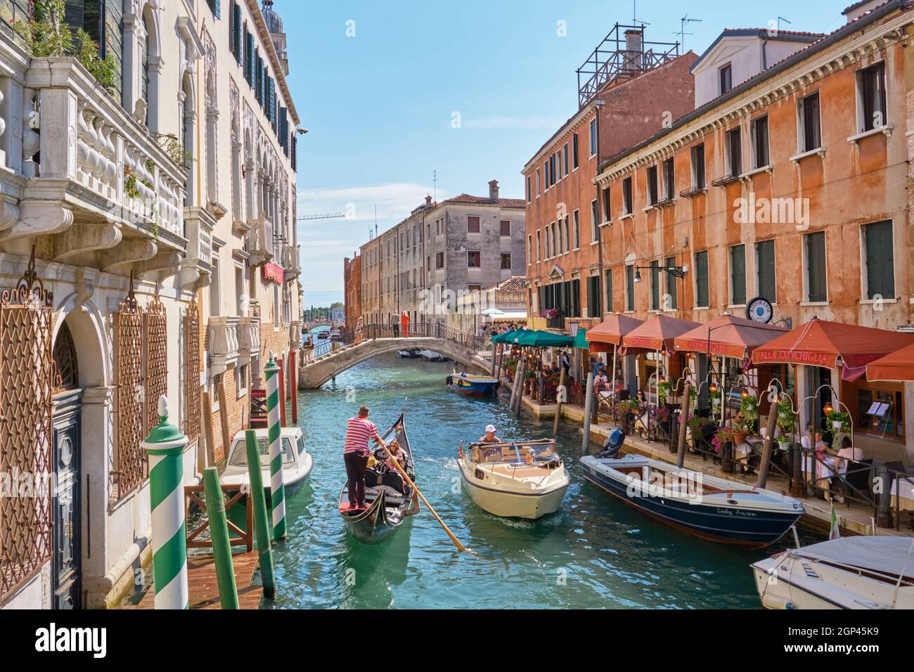 Vue sur un canal de Venise avec un restaurant, une gondole et un bateau à moteur. Venise, Italie Banque D'Images