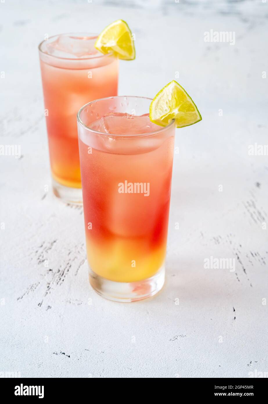 Deux verres de cocktail Bay Breeze garnis de quartiers de citron vert sur fond en bois Banque D'Images