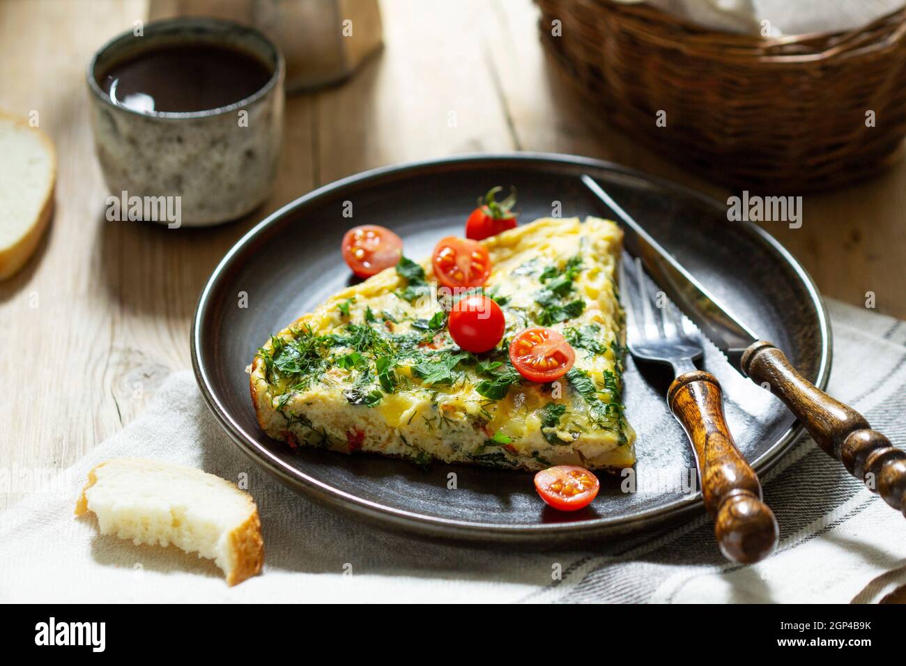 Petit-déjeuner composé d'omelettes aux légumes, aux herbes et au fromage, servi avec du pain et du café. Banque D'Images