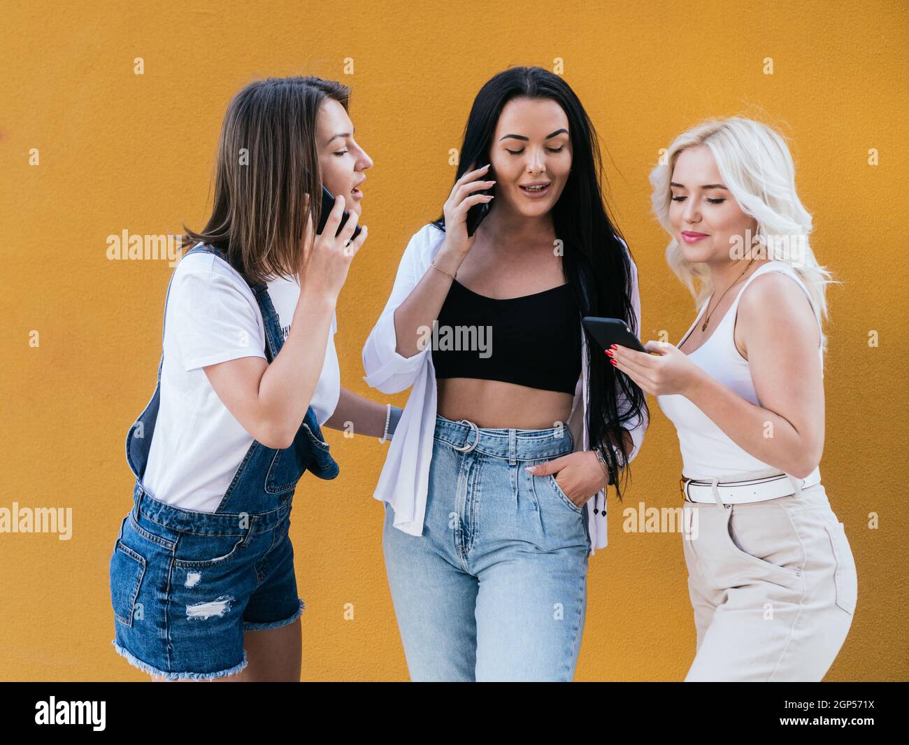 Trois jeunes amies utilisent leur téléphone portable tout en passant du temps ensemble. Banque D'Images