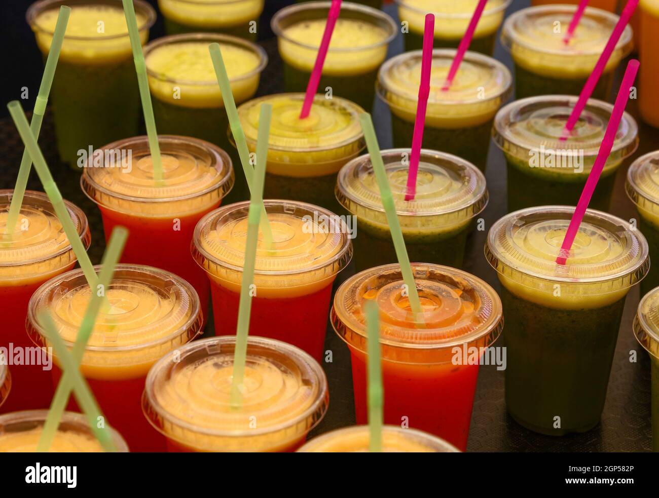 Gros plan de nombreux verres en plastique de jus de fruits et de légumes  frais et smoothies avec pailles à boire à l'exposition de détail, vue en  grand angle Photo Stock -