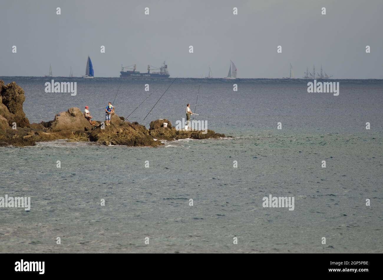 Risco Verde. Arinaga. Aguimes. Grande Canarie. Îles Canaries. Espagne. 24 novembre 2013 : pêcheurs et course transatlantique en arrière-plan. Banque D'Images