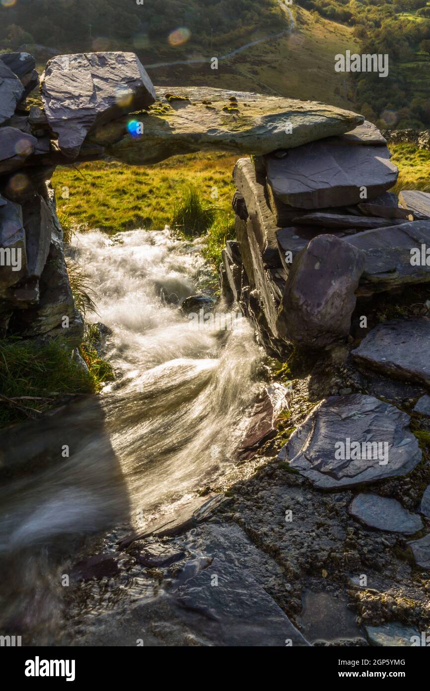 Cascade petit ruisseau qui a inondé le chemin après la pluie dans le trou dans le mur, flou obturateur lent, portrait. Banque D'Images