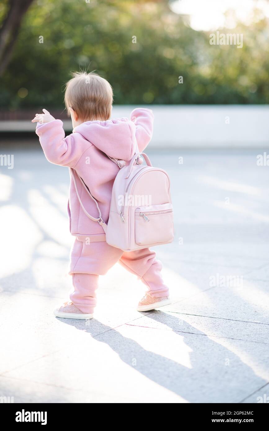 Drôle bébé fille 1 an porter élégant costume de sport rose et sac à dos  marcher dans la rue sur fond urbain. Joli petit enfant avec des vêtements  tendance. CHIL Photo Stock -
