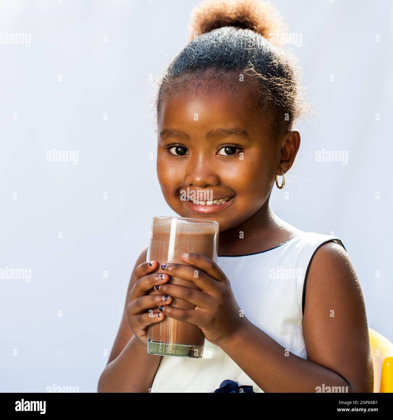 Gros plan portrait de l'adorable fille africaine buvant du lait boisson au chocolat.isolé sur fond clair. Banque D'Images