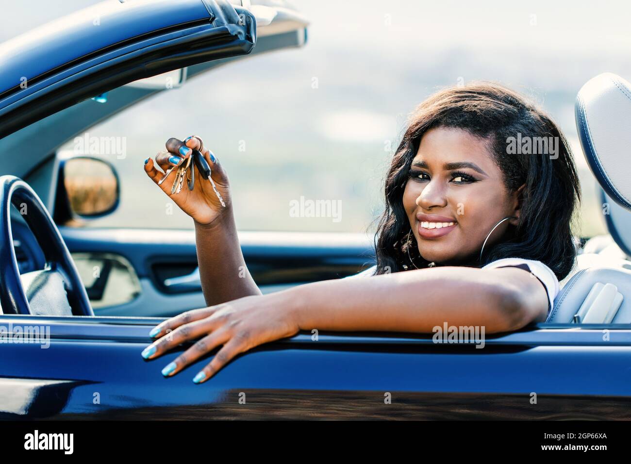 Gros plan d'une jeune femme africaine assise dans un cabriolet montrant les clés de la voiture. Banque D'Images