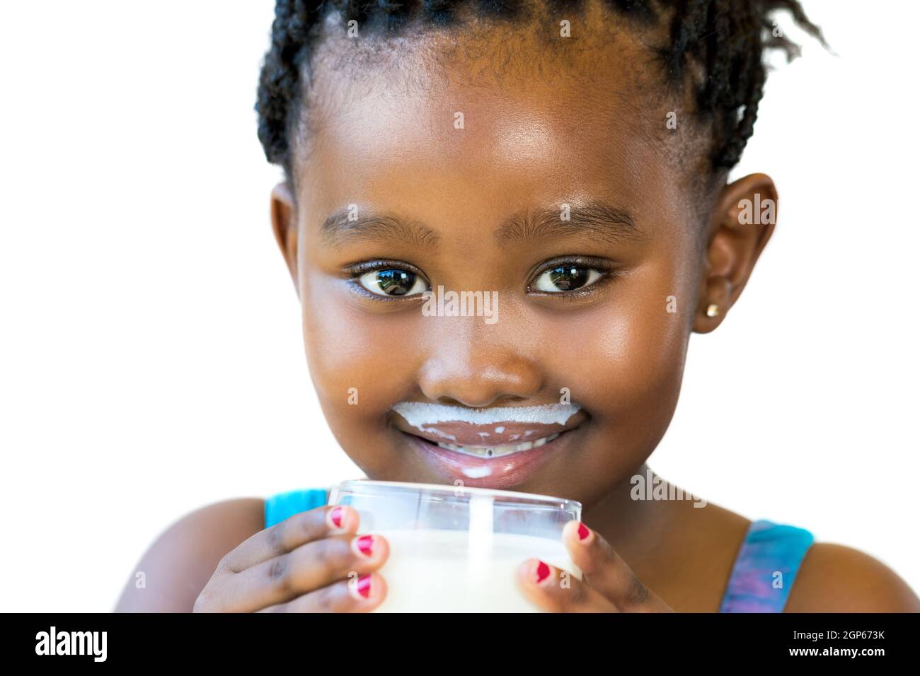 Gros plan de la petite fille africaine douce avec moustache en lait.fille tenant un verre de lait isolé sur fond blanc. Banque D'Images