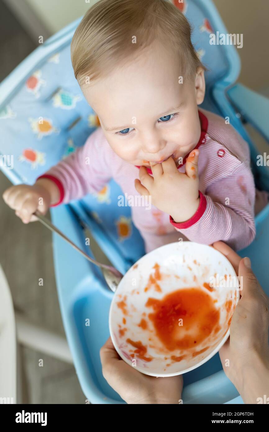 Mignon Heureux Adorable Bebe Garcon Profiter De S Asseoir Dans La Chaise Apprentissage Manger Avec Une Cuillere Et Une Assiette De Soupe De Legumes Saine Puree A La Cuisine Maison Photo Stock