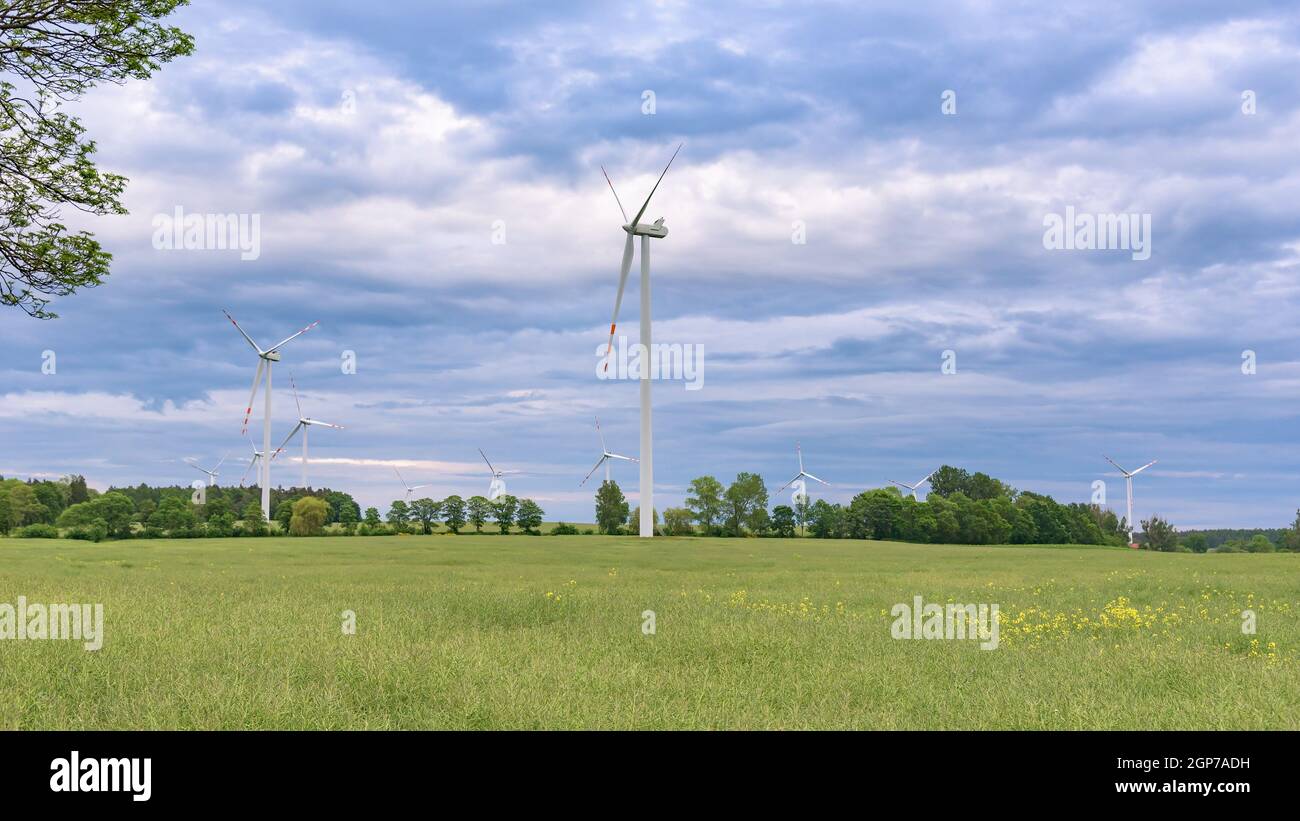 Éoliennes sur une ferme éolienne contre ciel nuageux à coucher de soleil Banque D'Images