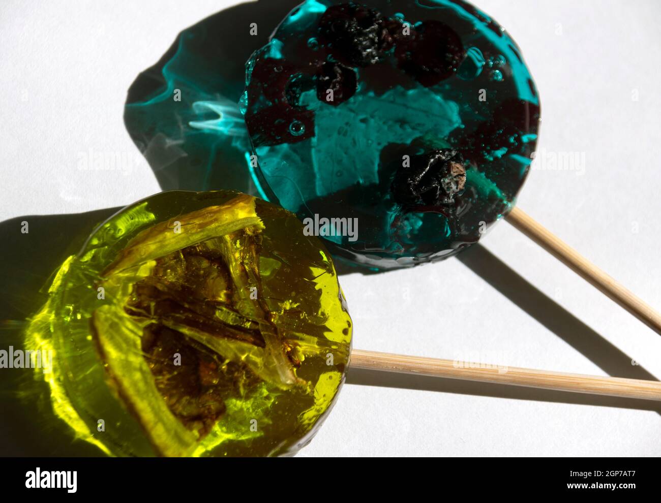 Lollipop avec cassis à l'intérieur de couleur turquoise et Lollipop avec tranche de citron jaune sur fond blanc. Banque D'Images