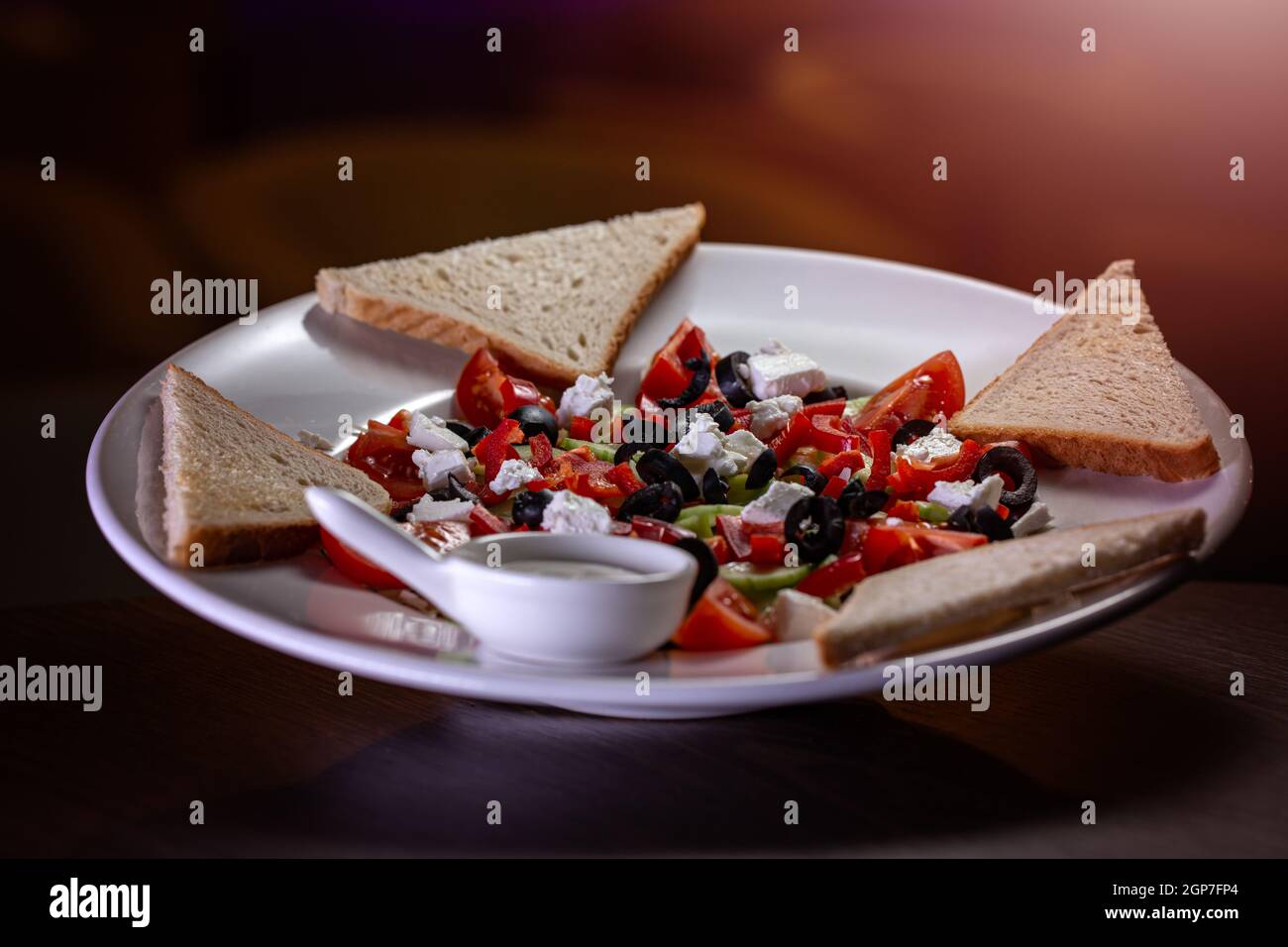 Salade grecque aux légumes frais, feta et olives noires servies avec du pain grillé et de la sauce Banque D'Images