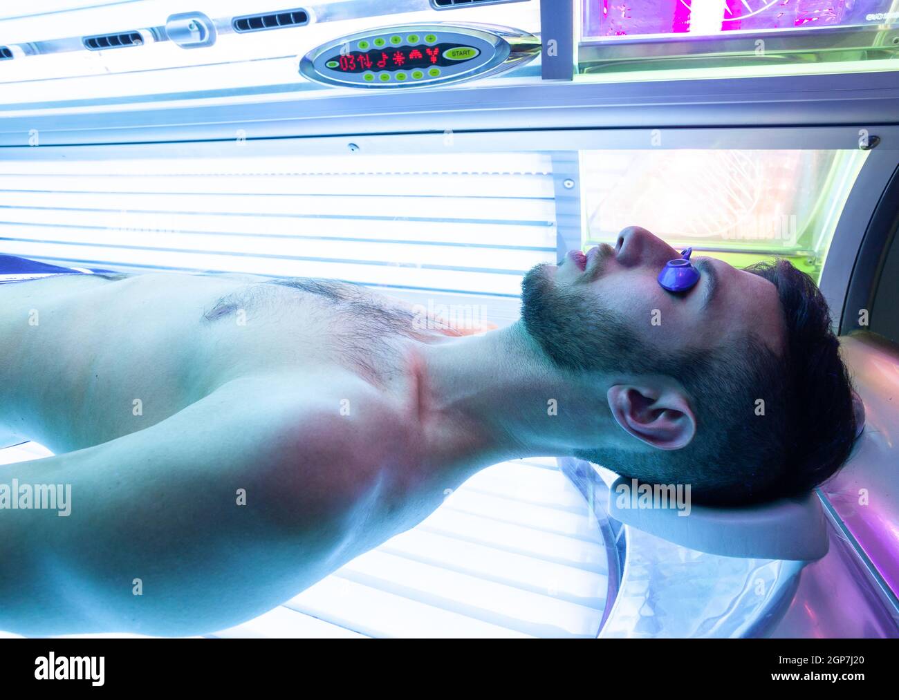 Jeune homme mince au solarium en instituts de beauté. Lit de bronzage intégral. Banque D'Images