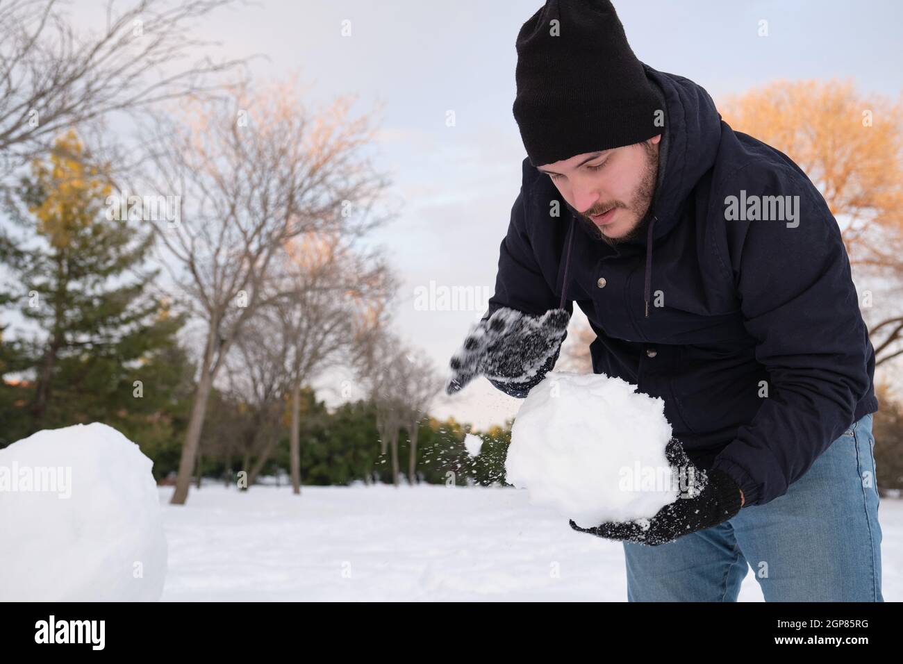 Un jeune homme de race blanche fait un bonhomme de neige Banque D'Images