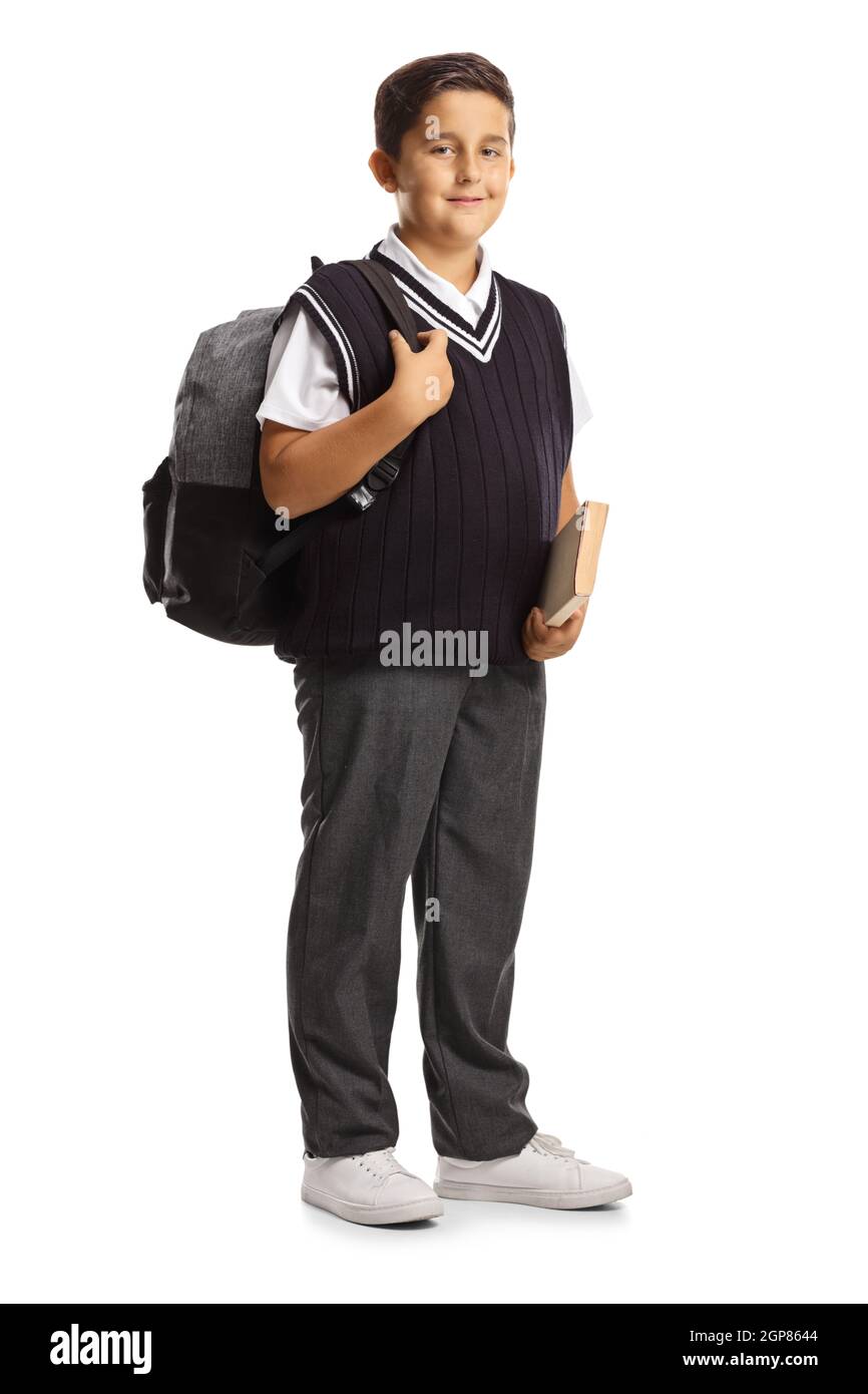 Portrait complet d'un élève mâle dans un uniforme d'école tenant un livre et portant un sac à dos isolé sur fond blanc Banque D'Images